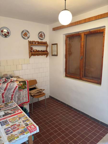 Kuchyně s kachličkami, ozdobnými talíři, dřevěným oknem, vhodná pro rekreační účely.