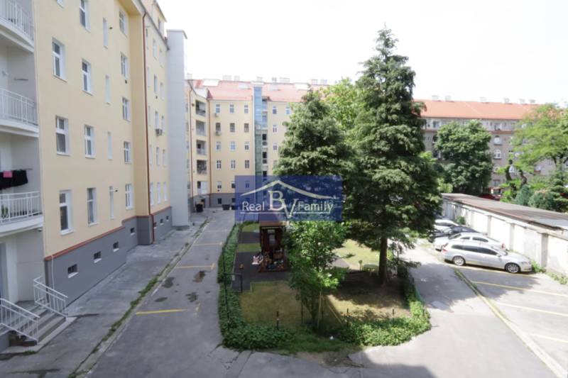 Dvůr bytového domu na Kalinčiakové v Bratislavě - Novém Městě s parkováním a hřištěm.