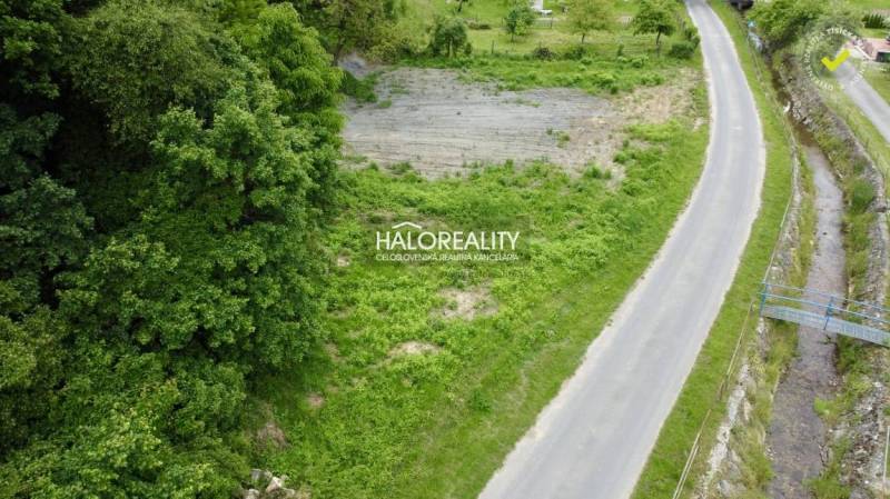 Pozemky na bydlení v Selcích u cesty, ohraničené zelení a potokem.