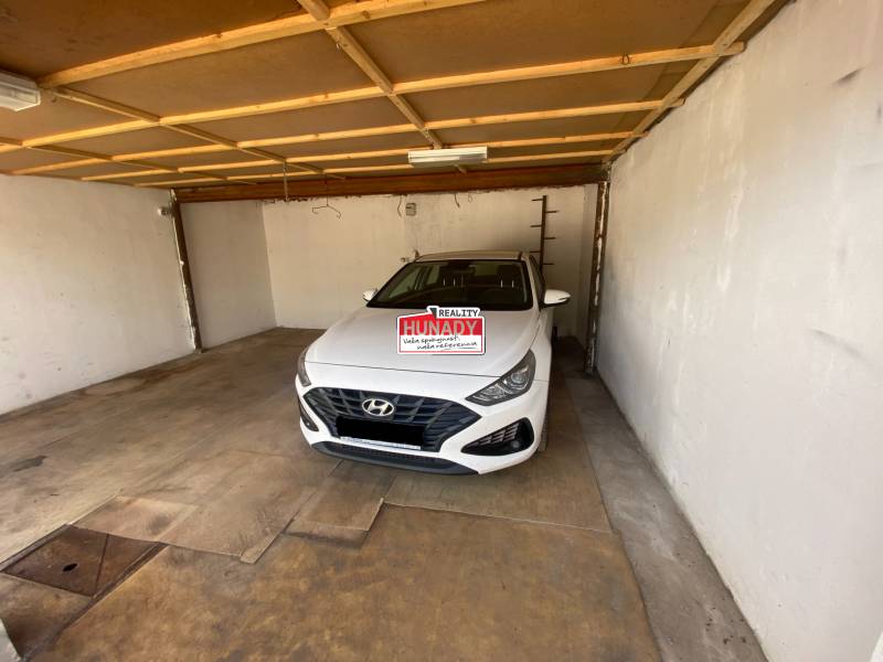 Interiér garáže s bílým autem značky Hyundai zaparkovaným uvnitř.