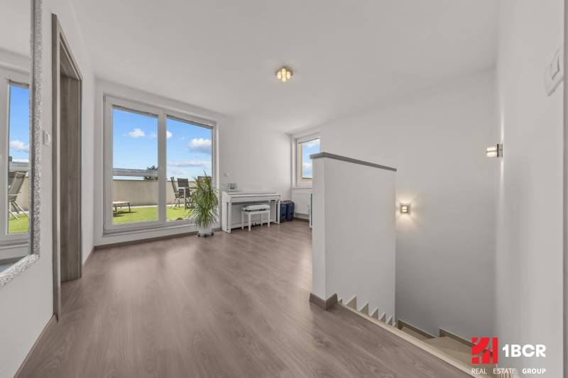Světlá chodba se schodištěm a přístupem na terasu ve 4-pokojovém bytě.