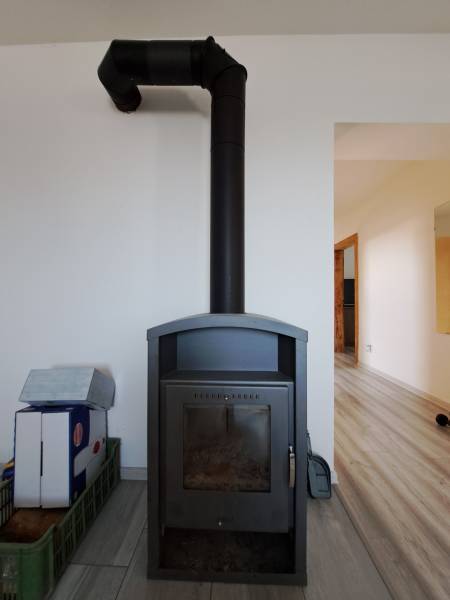 Krbová kamna v rodinném domě, minimalistický design ve světlém interiéru.