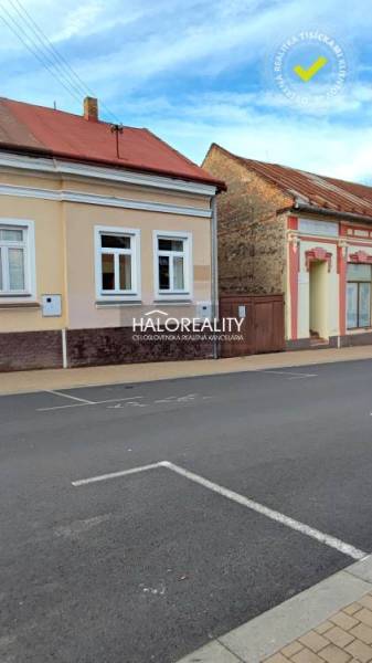 Rodinný dům v Lučenci s fasádou v jemných odstínech. Na ulici je volné parkování.