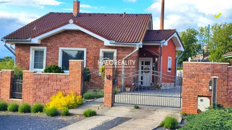 Rodinný dům v Kalinově s cihlovou fasádou, ozdobným plotem a zahradními prvky.