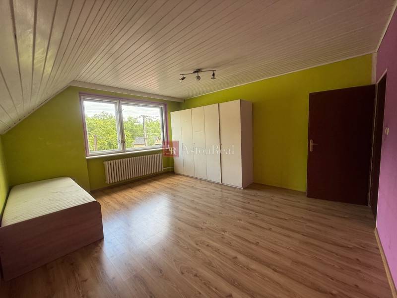 Pokoj v rodinném domě s laminátovou podlahou, barevnými stěnami, postelí a šatníkem.