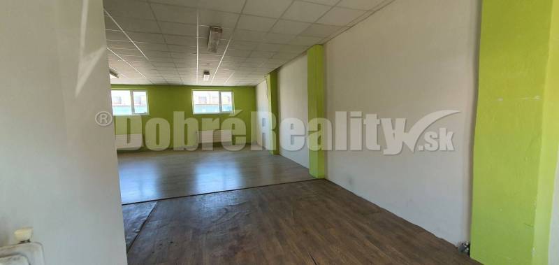 Interiér obchodních prostor s dřevěnou podlahou a zelenými stěnami, připravený k pronájmu.