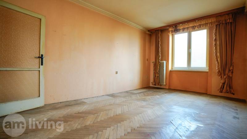 Prostorný pokoj s parketami a oknem v 2pokojovém bytě.