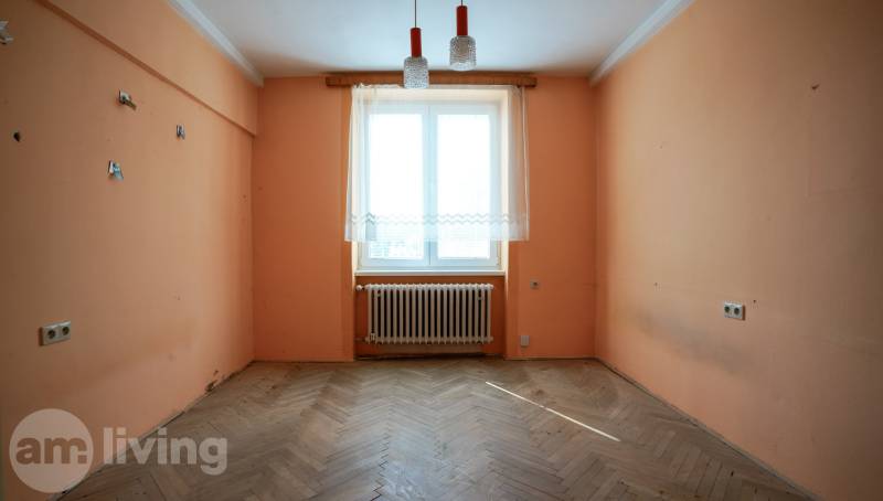 Prázdný pokoj v 2-pokojovém bytě s oranžovými stěnami a dřevěnou podlahou.