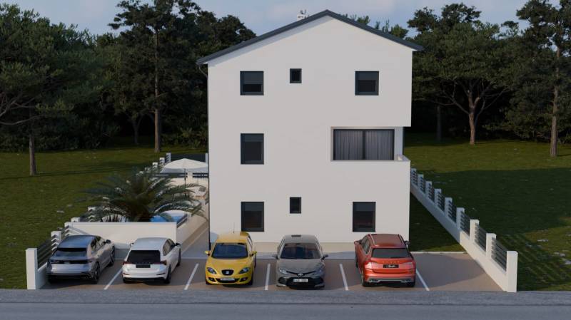 Parkoviště u čtyřpokojového bytu v Mandre s pěti auty před bílou budovou.