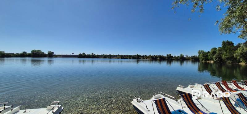 Jezero s vodními šlapadly v Bratislavě - Vajnorech, obklopené zelení a jasnou oblohou.