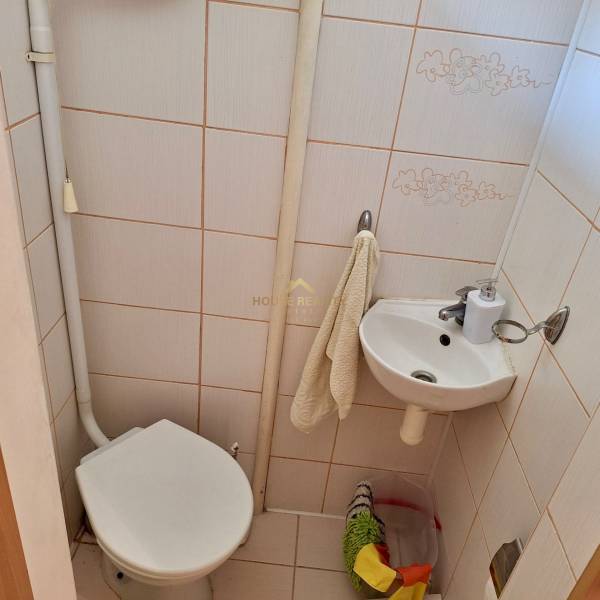 Toaleta a umyvadlo v koupelně 1pokojového bytu s béžovými obklady.