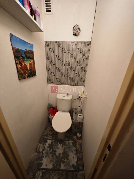 Toaleta s květinovou dekorací a kalendářem v 2-pokojovém bytě.