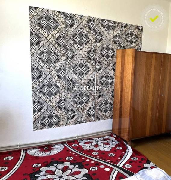 Černobílá geometrická tapeta, dřevěná skříň a květinový koberec v rodinném domě.