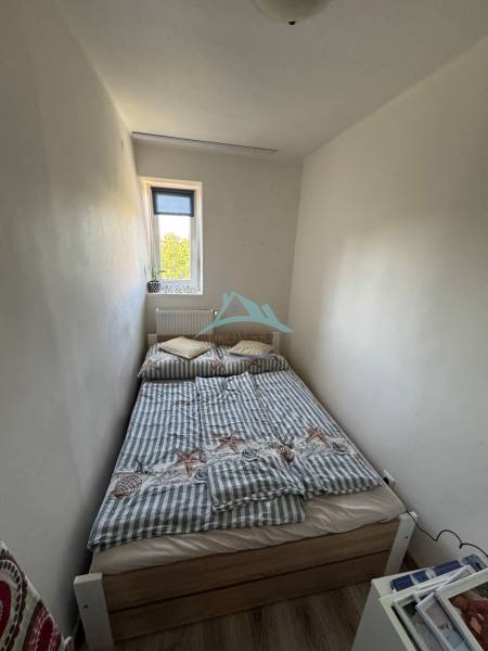 Malá ložnice s úzkým oknem a postelí v 3-pokojovém bytě.