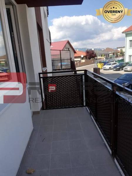 Balkon 2-pokojového bytu na ulici Slavomírova, výhled na okolní zástavbu a auta.