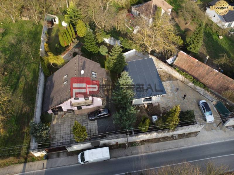 Rodinný dům v Píle se zahradou, příjezdovou cestou a parkovištěm, obklopený zelení.