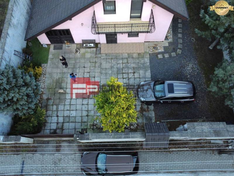 Rodinný dům v Píle s prostorným dvorem, zaparkovanými auty a udržovanou zahradou.
