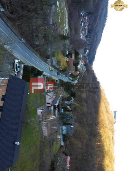 Rodinné domy v obci Píla, lemované cestou a lesem.