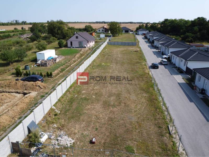 Pozemky - bydlení ve Štefanové, vedle prázdná parcela, obklopené venkovskými domy a zelení.