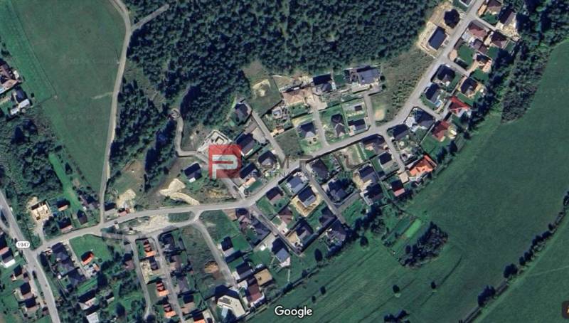 Letecký pohled na pozemky - bydlení v Pružině obklopené zelenými plochami a lesem.