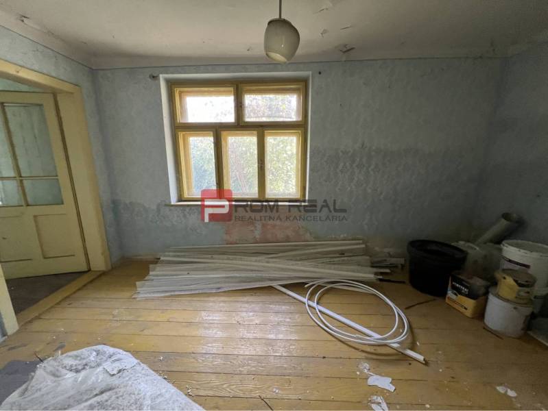 Místnost s dřevěnou podlahou, staré dveře, stavební materiál, slouží k rekonstrukci. Pozemky - bydlení.