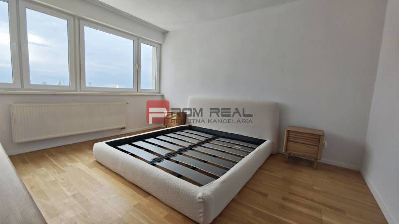 Světlá ložnice s dřevěnou podlahou a postelí ve 4pokojovém bytě.