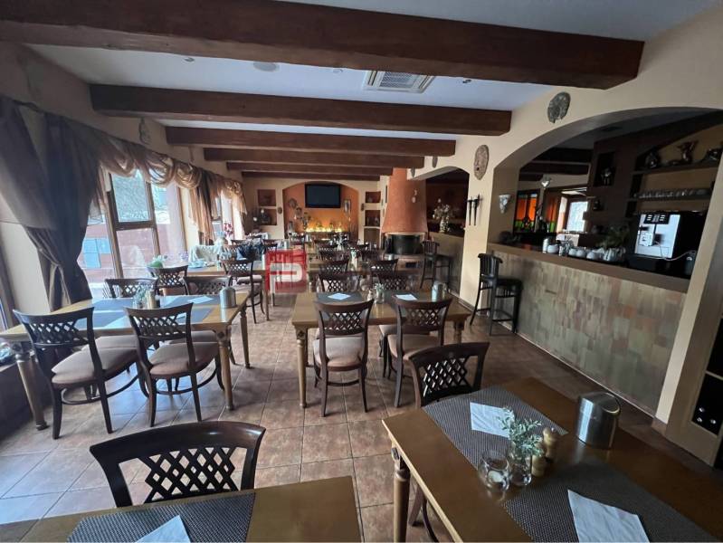Restaurace v hotelové části s dřevěnými trámy, stoly a židlemi. Hotely a penziony.
