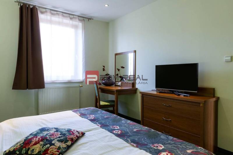 Pokoj s postelí, stolkem a televizí v hotelu a penzionu.