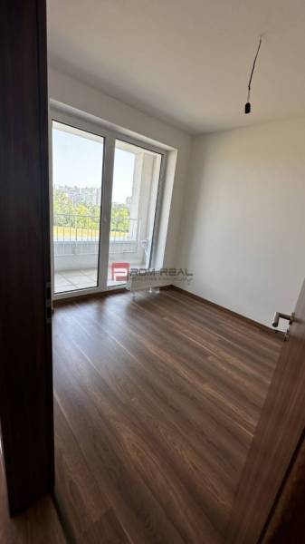 Pokoj s dřevěnou podlahou a balkonem ve 2pokojovém bytě.