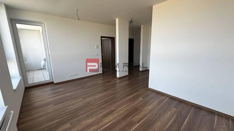 Interiér 2-pokojového bytu s dřevěnou podlahou a prostorným balkonem.