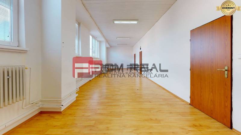 Prostorná chodba s dřevěnou podlahou a dveřmi ve skladových a halových prostorách.