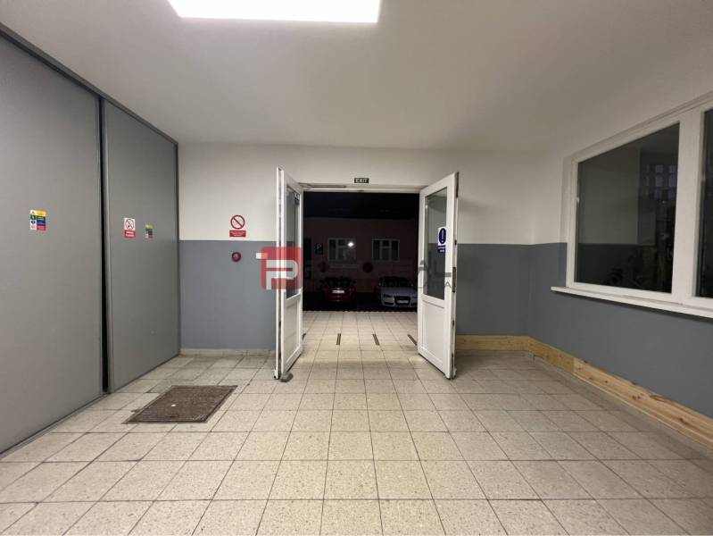 Vstupní chodba uvnitř skladů a hal s výstupem na parkoviště.