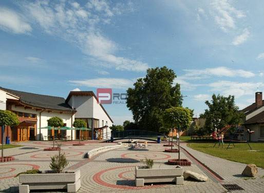 Dvůr v Rovince na ulici Centrum, s přilehlými budovami a dětským hřištěm.