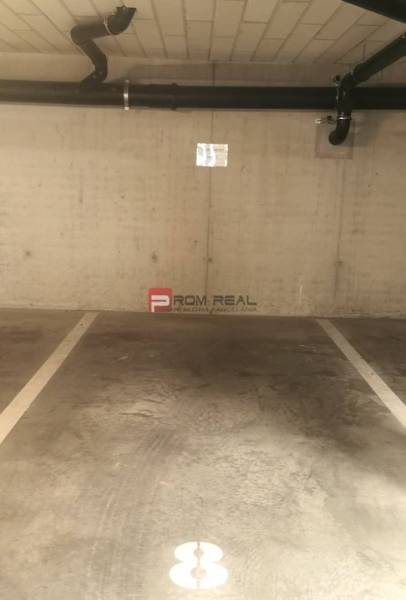 Parkovací místo v garážích s potrubím na stěně.