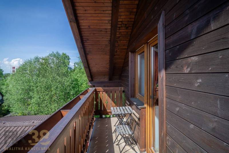 Balkon se stolem a židlemi v Rekreačním apartmánu s výhledem na stromy ve Vysokých Tatrách.