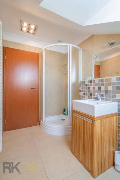 Koupelna v rekreačním apartmánu se sprchovým koutem a čtvercovým umyvadlem.
