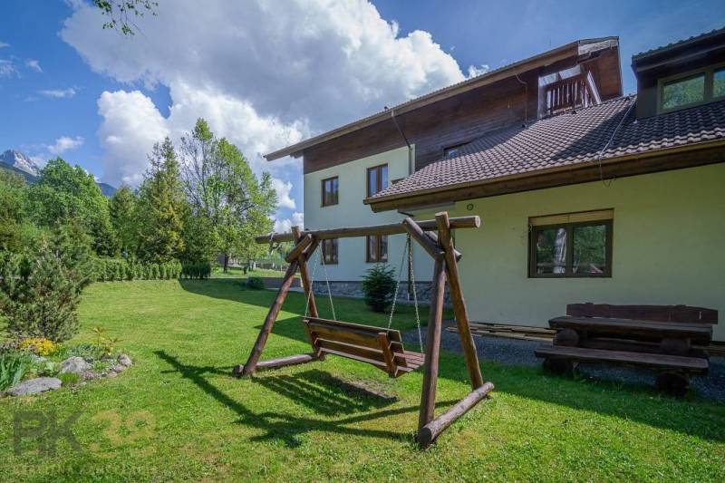 Zahrada s dřevěnou houpačkou a lavičkou u Rekreačního apartmánu ve Vysokých Tatrách.