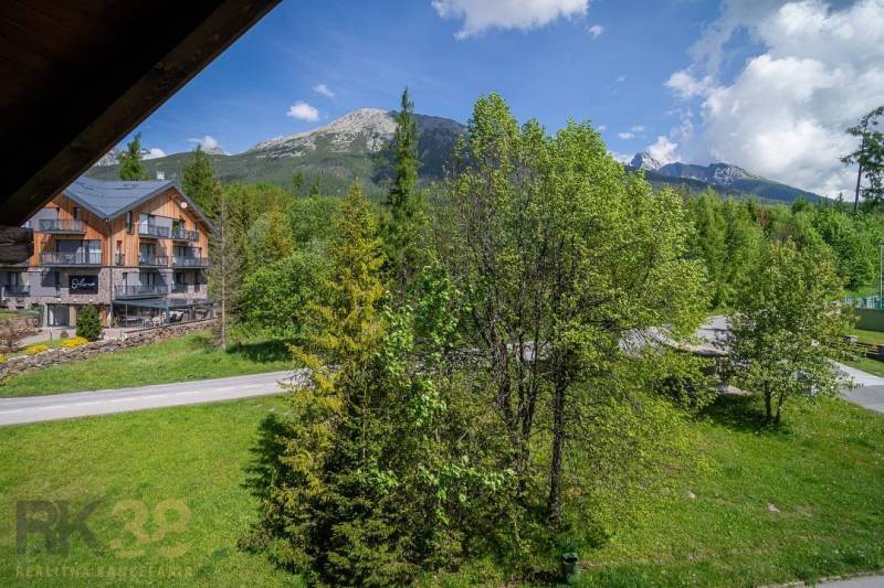 Výhled z rekreačního apartmánu ve Vysokých Tatrách, s horami a zelenými stromy.