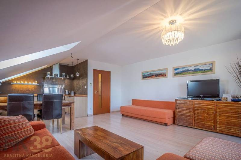 Obývací pokoj rekreačního apartmánu s pohovkami, jídelním stolem a televizí.
