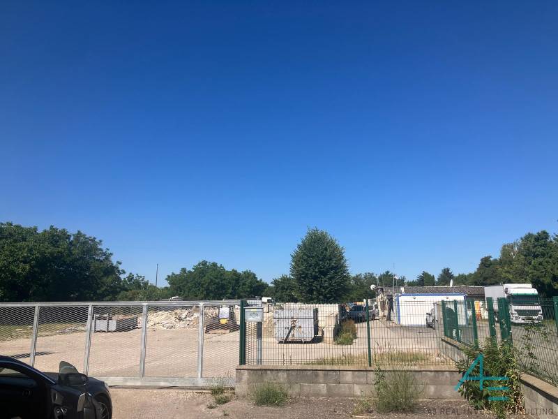 Pozemky - komerční na Popradské ulici v Bratislavě - Podunajské Biskupice s bránou a kontejnery.
