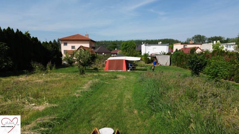 Zahrada s trávníkem v Dolním Baru, s výhledem na domy a stan. Pozemky - bydlení.