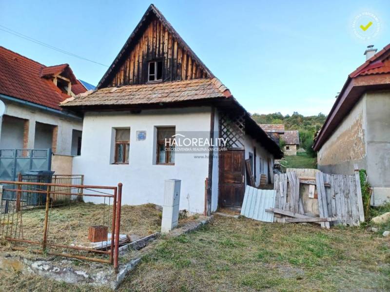 Rodinný dům v Ladzanech se šikmou střechou a zahradou, obklopený dalšími stavbami.
