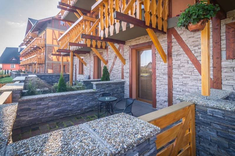 Rekreační apartmán ve Velké Lomnici s kamennou terasou a dřevěnými balkony.