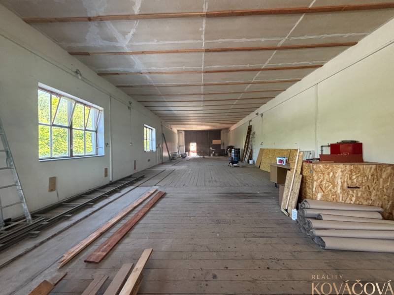 Interiér skladů a hal s dřevěnou podlahou, regály a stavebním materiálem.