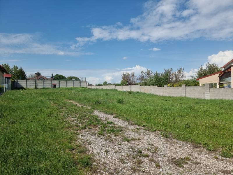 Pozemek k bydlení v Cabaji-Čápore obklopený travnatým prostředím a ploty pod modrou oblohou.