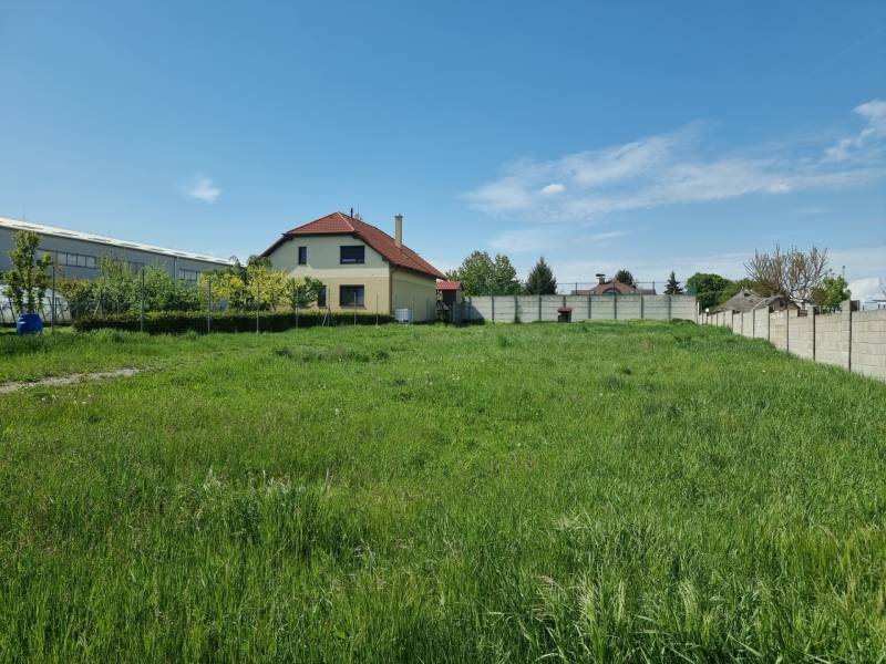 Pozemky - bydlení v Cabaji-Čápore s travnatou plochou a domem v pozadí.