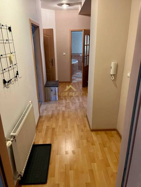 Chodba v 2-pokojovém bytě s dřevěnou podlahou, věšákem, vstupem do koupelny.