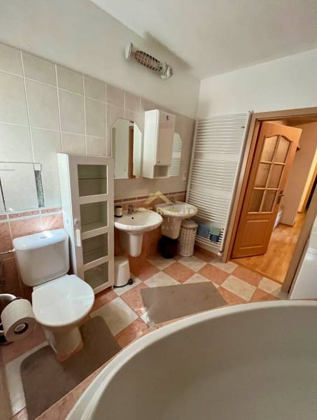 Koupelna dvoupokojového bytu se sanitou, skříňkami a velkou vanou.