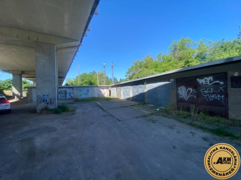 Garáže ve Zvolenu pod mostem s graffiti na stěnách a zaparkovaným autem.