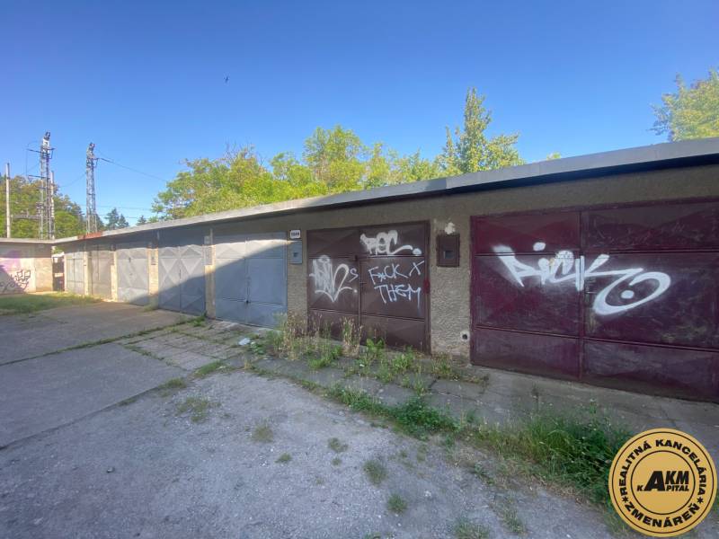 Garáže ve Zvolenu s graffiti na vratech, obklopené zelení a betonovou plochou.
